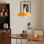 Glass pendant light with ring shade, yellow, above a dining nook