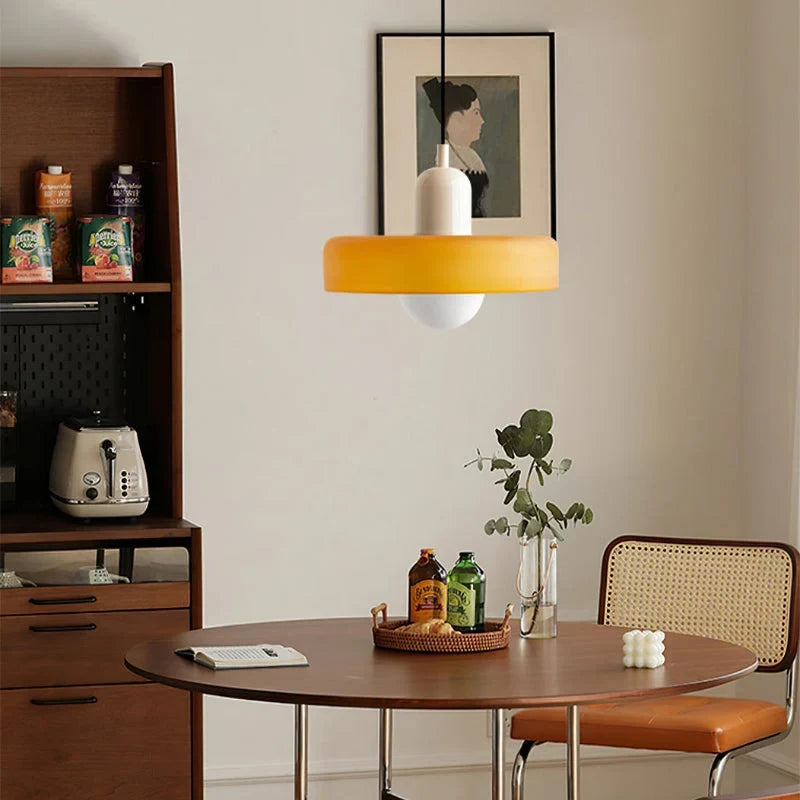 Glass pendant light with ring shade, yellow, above a dining nook