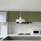 Glass pendant light with ring shade, white, above a kitchen
