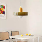 Glass pendant light with ring shade, yellow, above a dining table