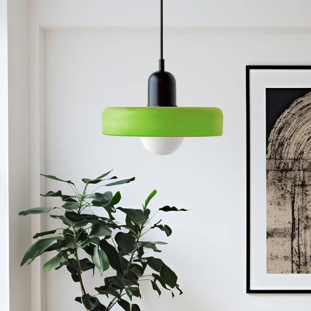 Glass pendant light with ring shade, green, beside a plant