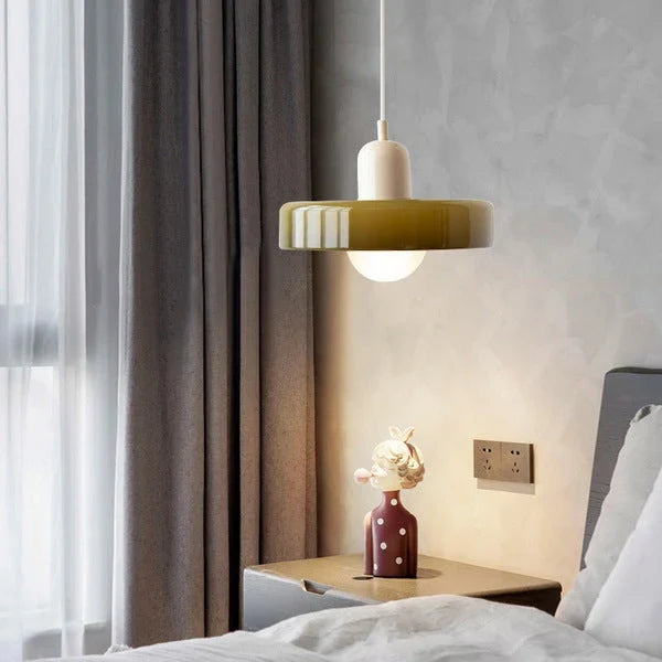 Glass pendant light with ring shade, army green, beside a bed