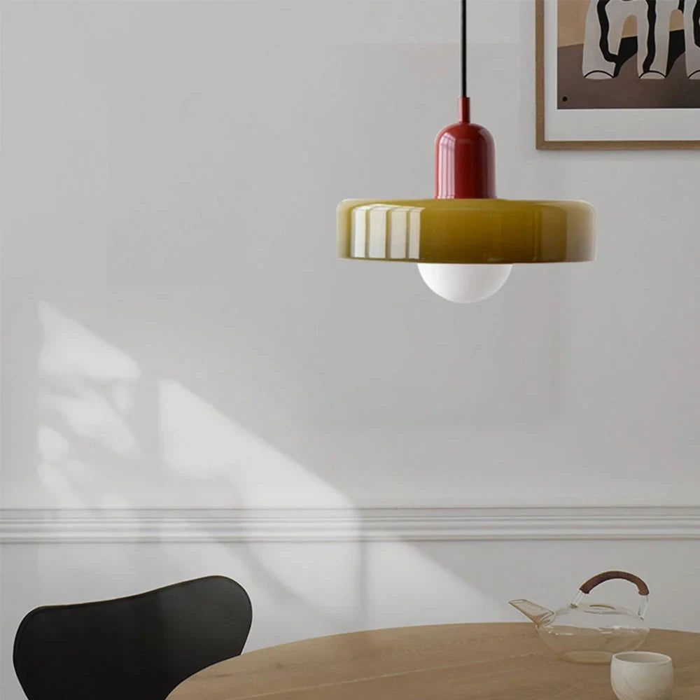 Glass pendant light with ring shade, army green, above a table
