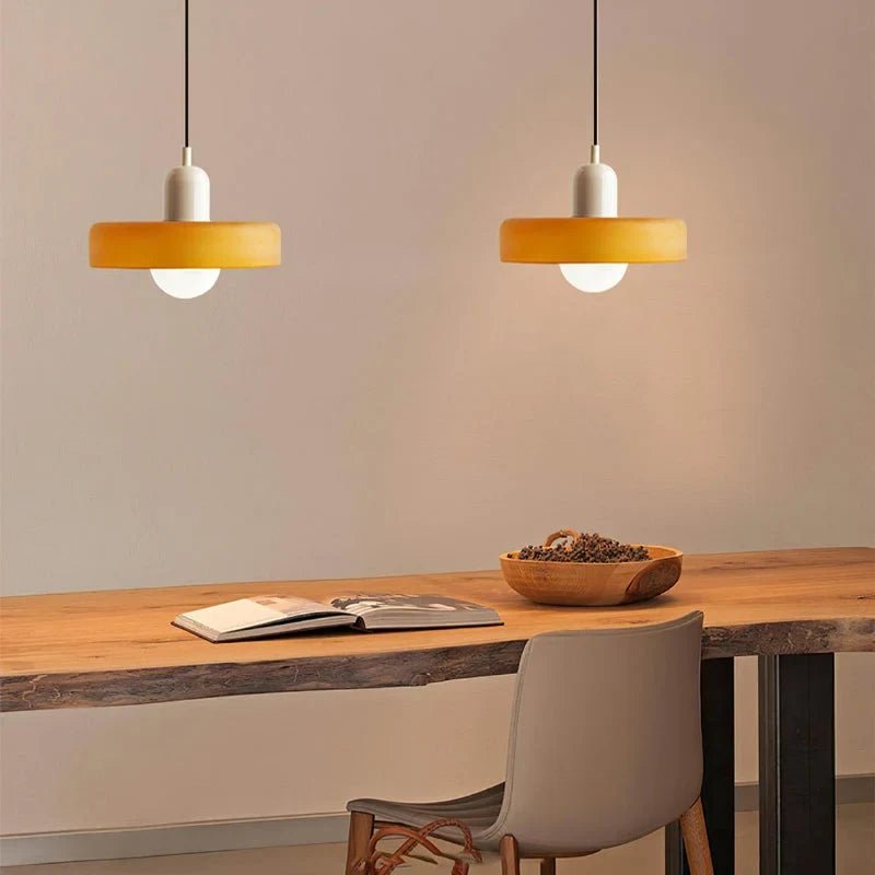 Glass pendant light with ring shade, yellow pair above a table