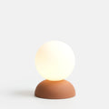 Glazed stoneware globe table lamp, in terracotta, lit