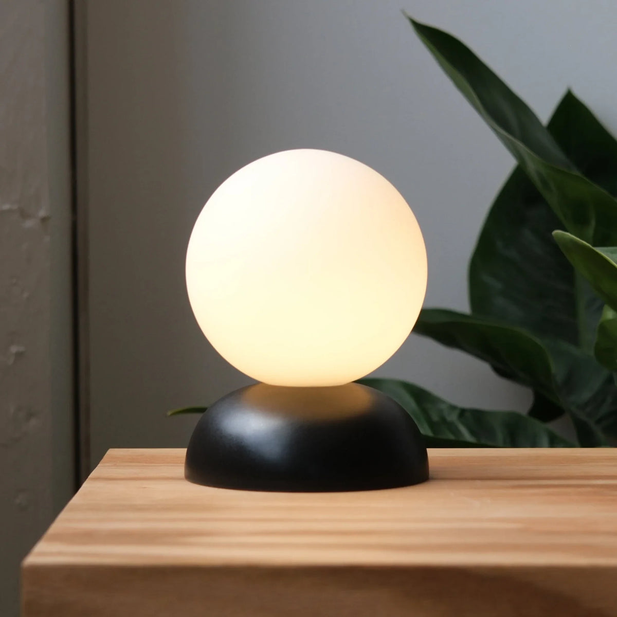Glazed stoneware globe table lamp, in black, lit