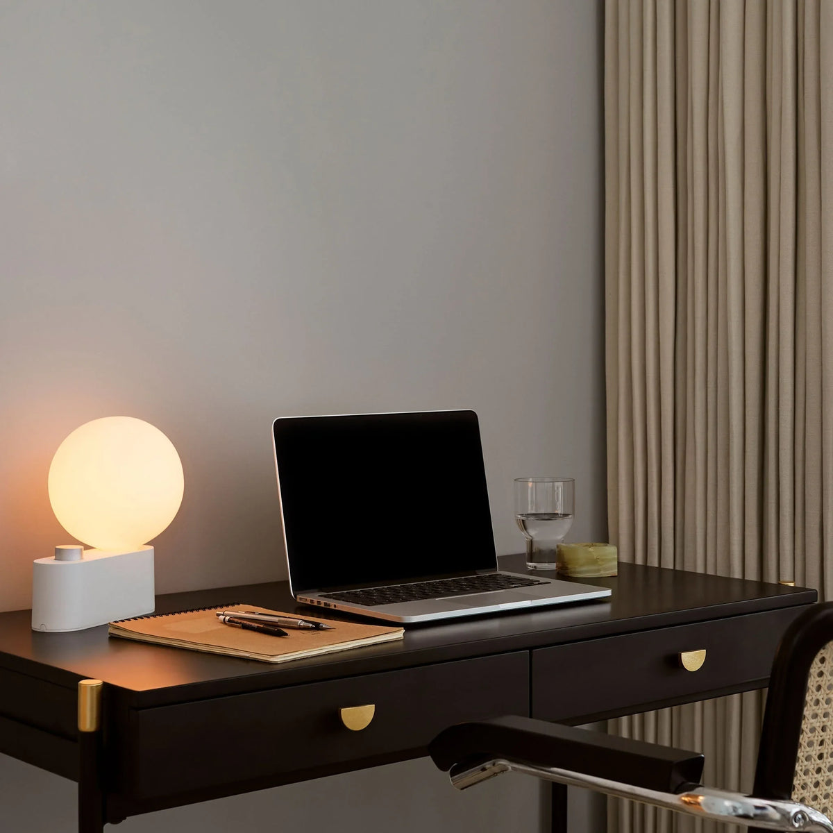 Globe table lamp or wall light, chalk, on a desk beside a laptop