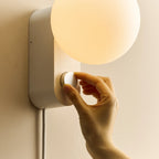 Globe table lamp or wall light, chalk, a hand adjusting the dial on the wall-mounted lamp