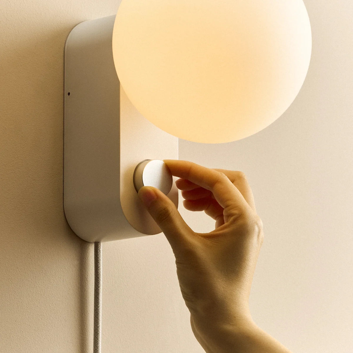 Globe table lamp or wall light, chalk, a hand adjusting the dial on the wall-mounted lamp