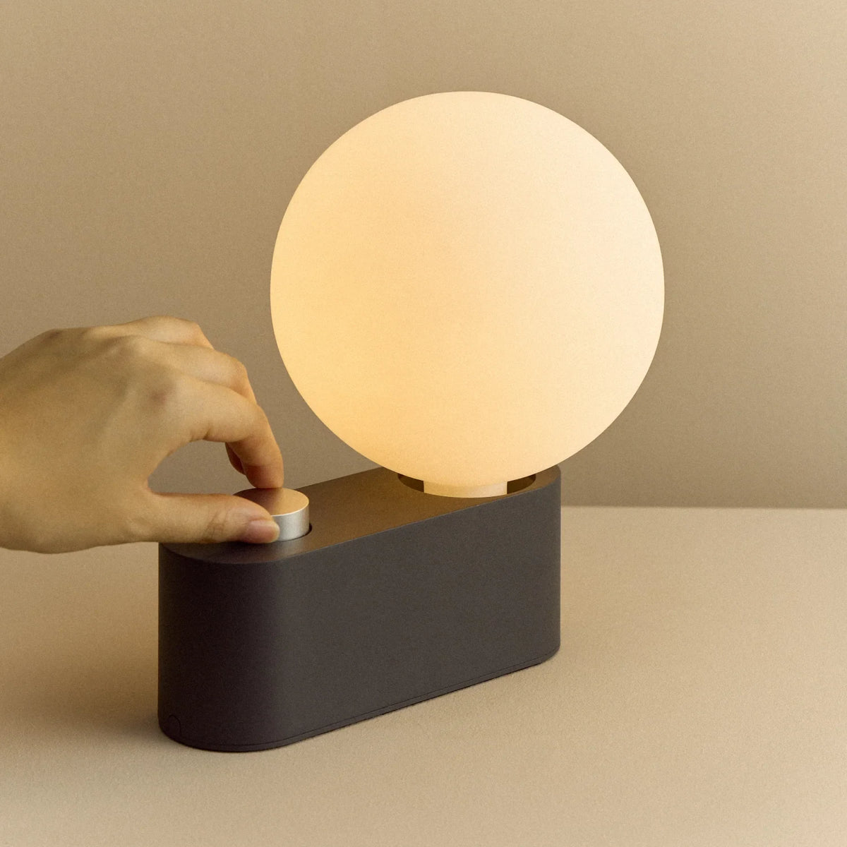 Globe table lamp or wall light, charcoal, set of 2, a hand adjusting the dial