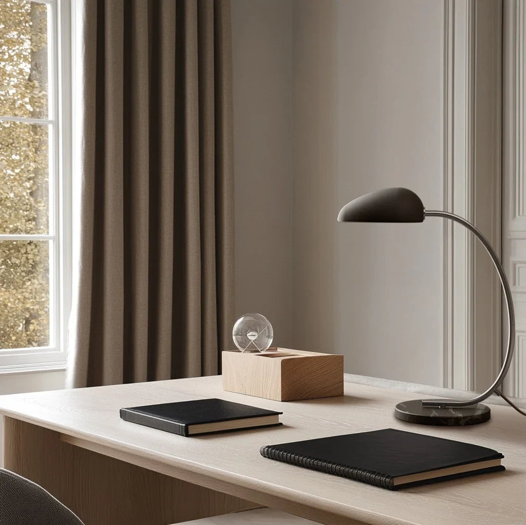 Gooseneck table lamp with marble base, on a desk, with a dark grey shade