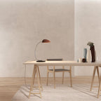 Gooseneck table lamp with marble base, on a desk, with a terracotta shade