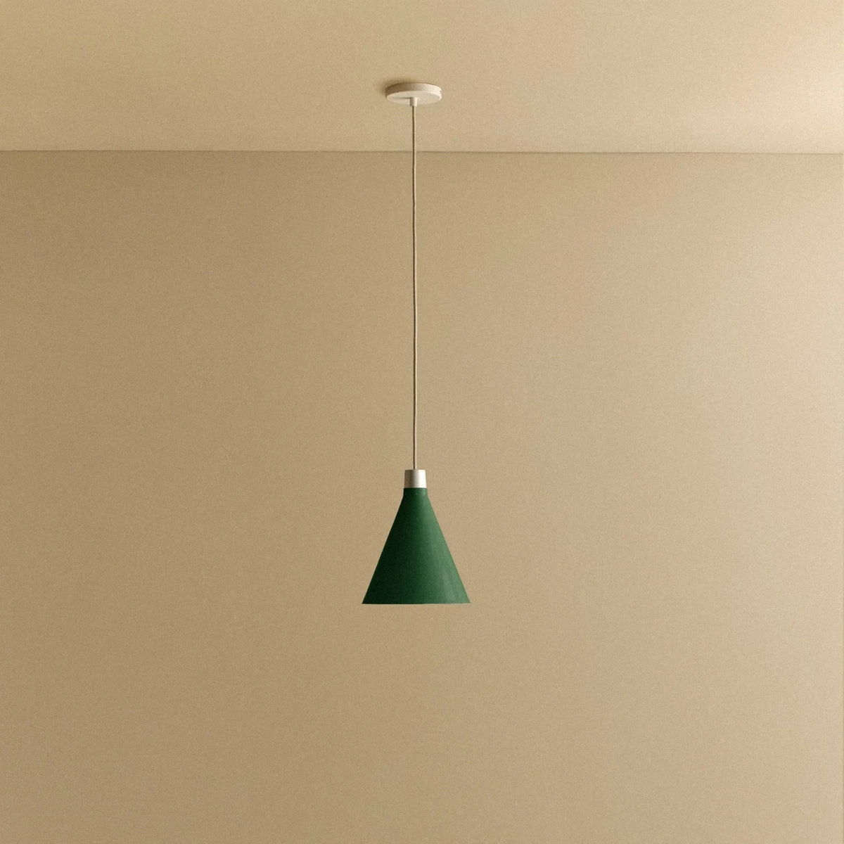 Dark Green cone pendant, small, with matte white dim-to-warm bulb, lit, against a plain wall