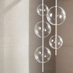 Hand-blown glass globe pendant on a steel stem, group of clear glass globes at different heights