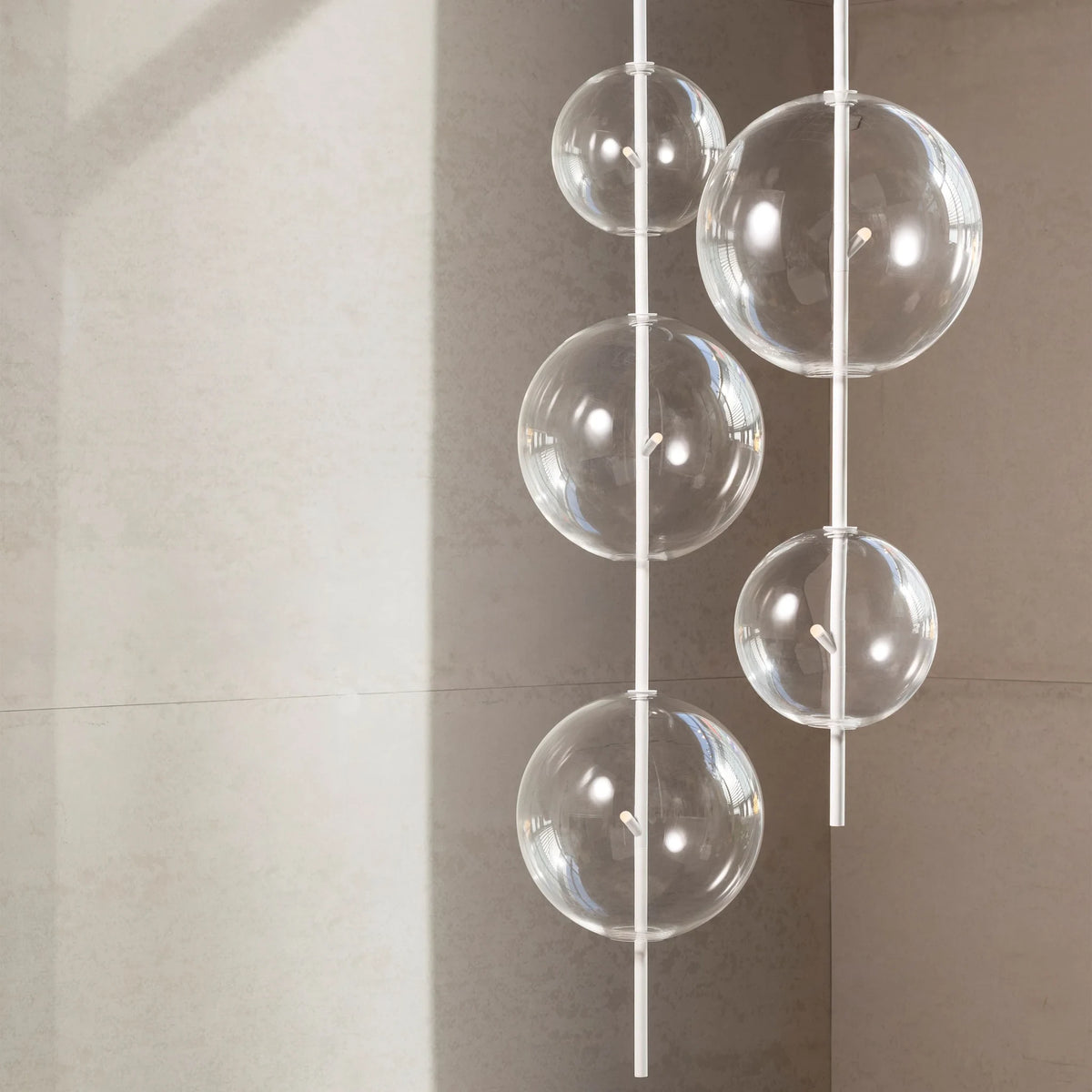 Hand-blown glass globe pendant on a steel stem, group of clear glass globes at different heights