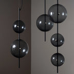 Hand-blown glass globe pendant on a steel stem, group of smoke grey globes at different heights