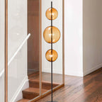 Modular hand-blown glass globe floor lamp, in amber glass beside a staircase