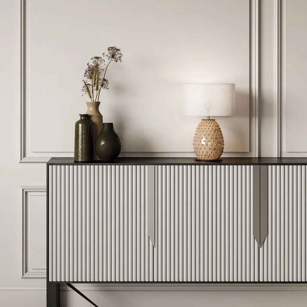 Hand-painted bobble glass table lamp with drum shade, in a warm tan on a ribbed sideboard