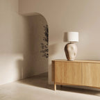 Hand-painted ceramic table lamp with rounded dimpled body, in a room with an arched doorway, with a shade (sold separately)