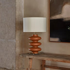 Hand-painted wavy ceramic table lamp, in terracotta on a wooden console
