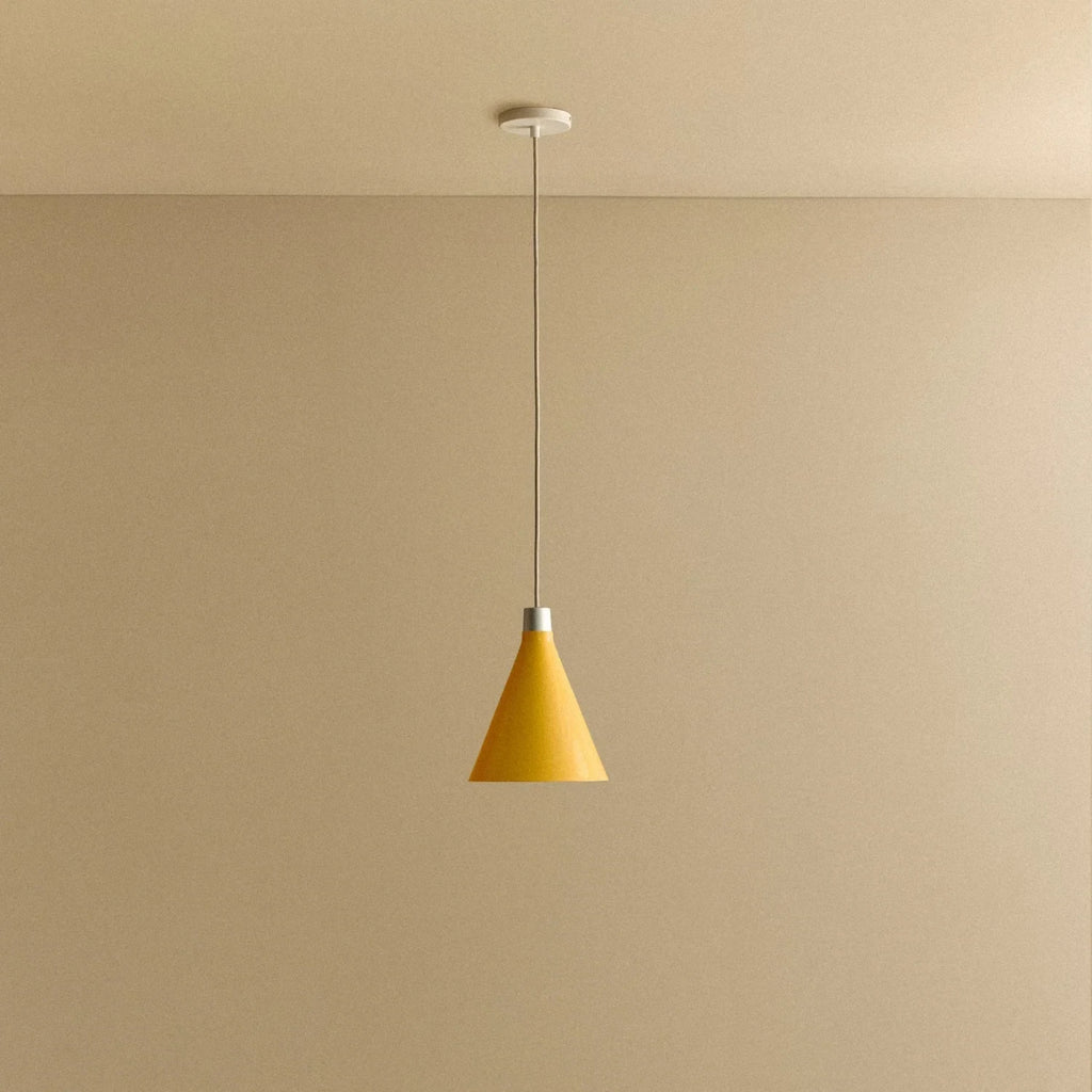 Small yellow hand-spun steel cone pendant, against a plain wall