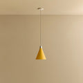 Small yellow hand-spun steel cone pendant, against a plain wall