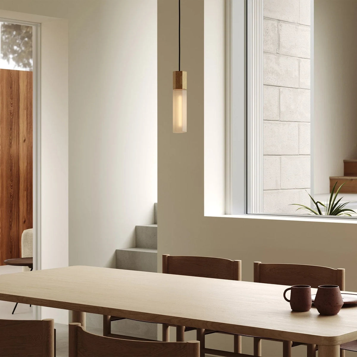 Hexagonal cast brass pendant with glass bulb, above a dining table