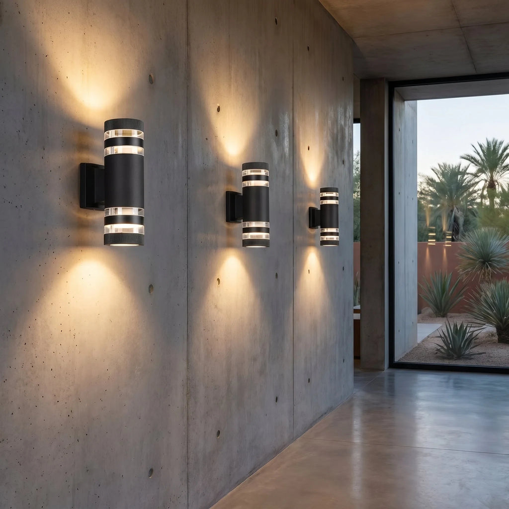 Outdoor up and down wall light in black, a row lit along a concrete wall