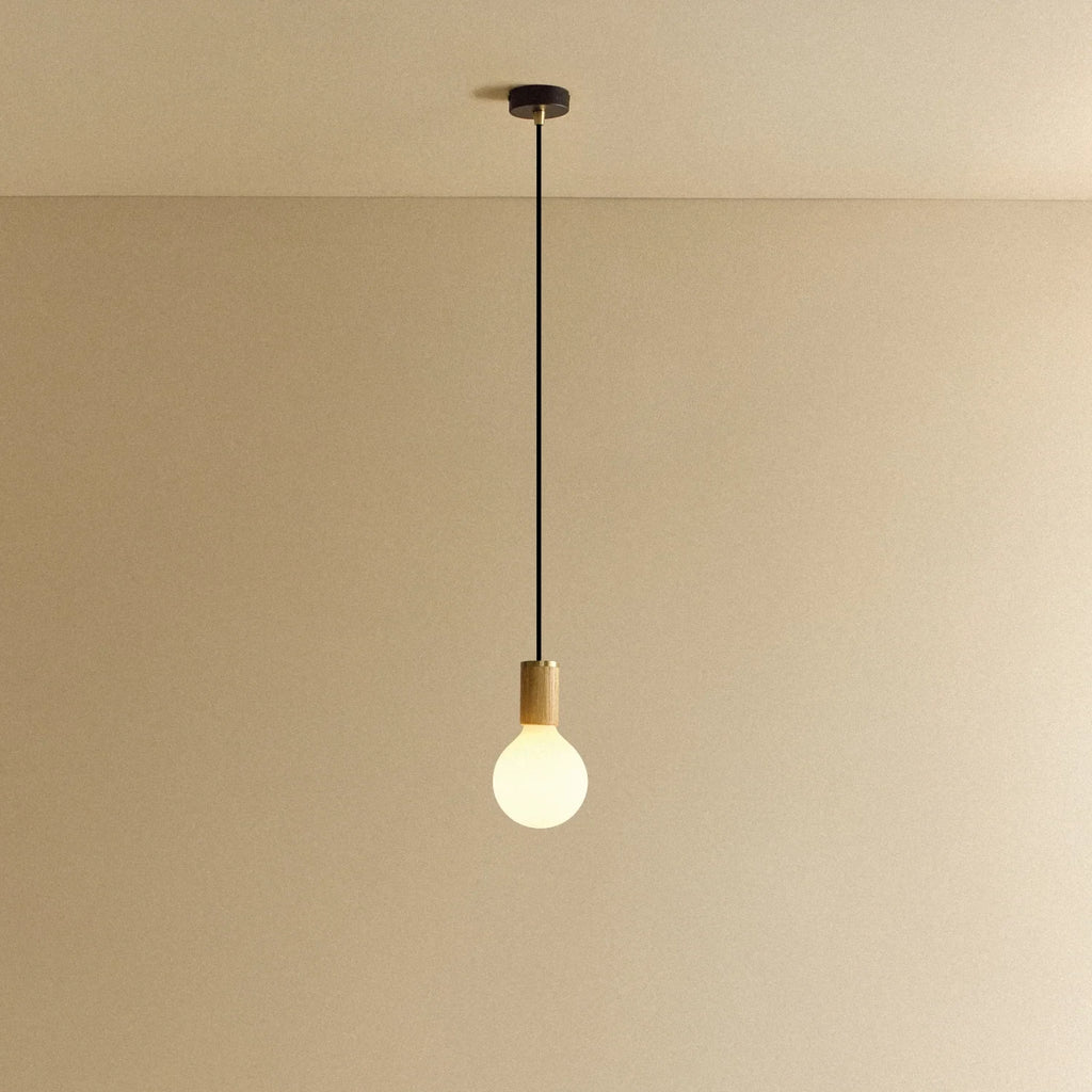 Large matte white globe pendant, oak, lit, against a plain wall