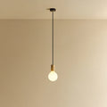 Large matte white globe pendant, oak, lit, against a plain wall