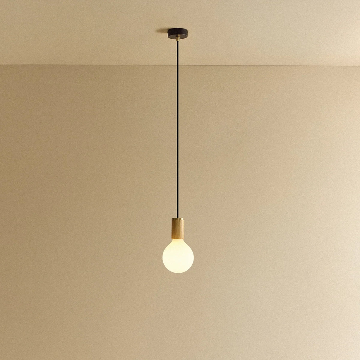Large matte white globe pendant, oak, lit, against a plain wall