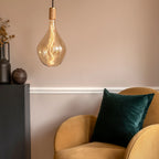 Large teardrop tinted glass pendant, oak, above an armchair in a living room