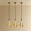 Set of three large teardrop tinted glass pendants, graphite, set of three lit, against a plain wall