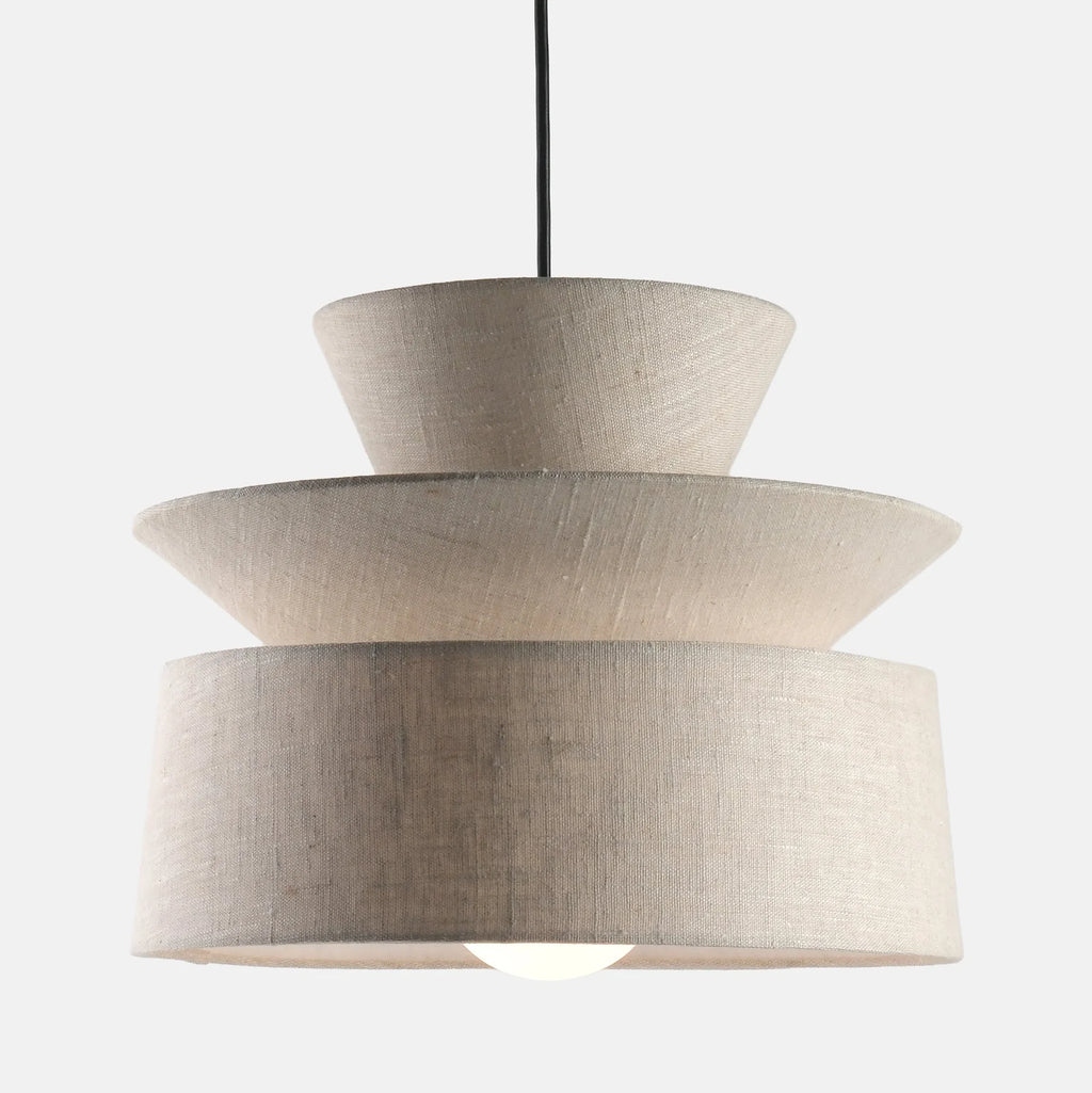 Layered cotton shade pendant, lit, on a pale background
