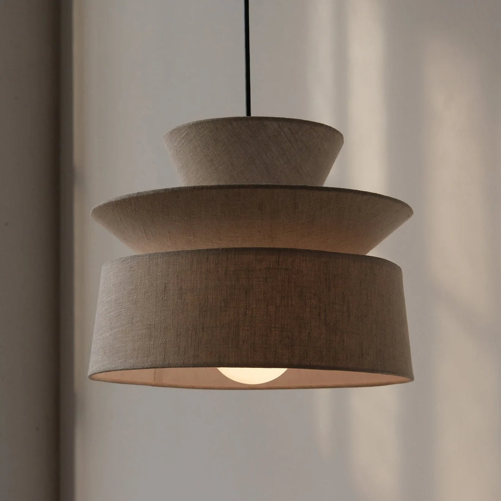 Layered cotton shade pendant, lit, against a wall