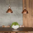 Library-style metal pendant, pair in copper above a table