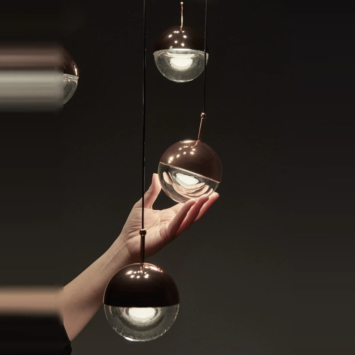 Linear glass globe pendant, five lights, close-up, one globe held in a hand