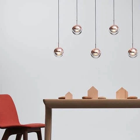 Linear glass globe pendant, five lights, in copper above a table
