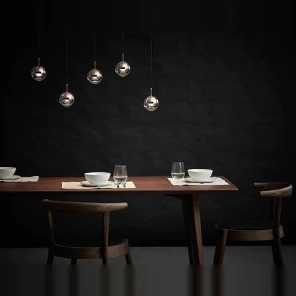 Linear glass globe pendant, five lights, above a dining table