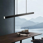 Linear LED pendant light, in black, over a dining table