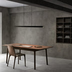 Linear LED pendant with touchless dimmer, in black above a dining table
