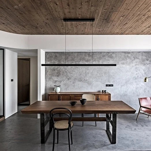Linear LED pendant with wood ends, above a dining table under a wooden ceiling