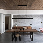 Linear LED pendant with wood ends, above a dining table under a wooden ceiling