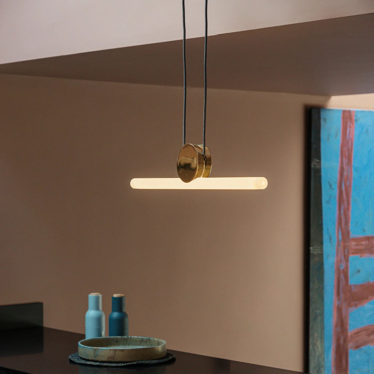 Linear LED tube pendant, set of 2, polished brass, lit over a counter