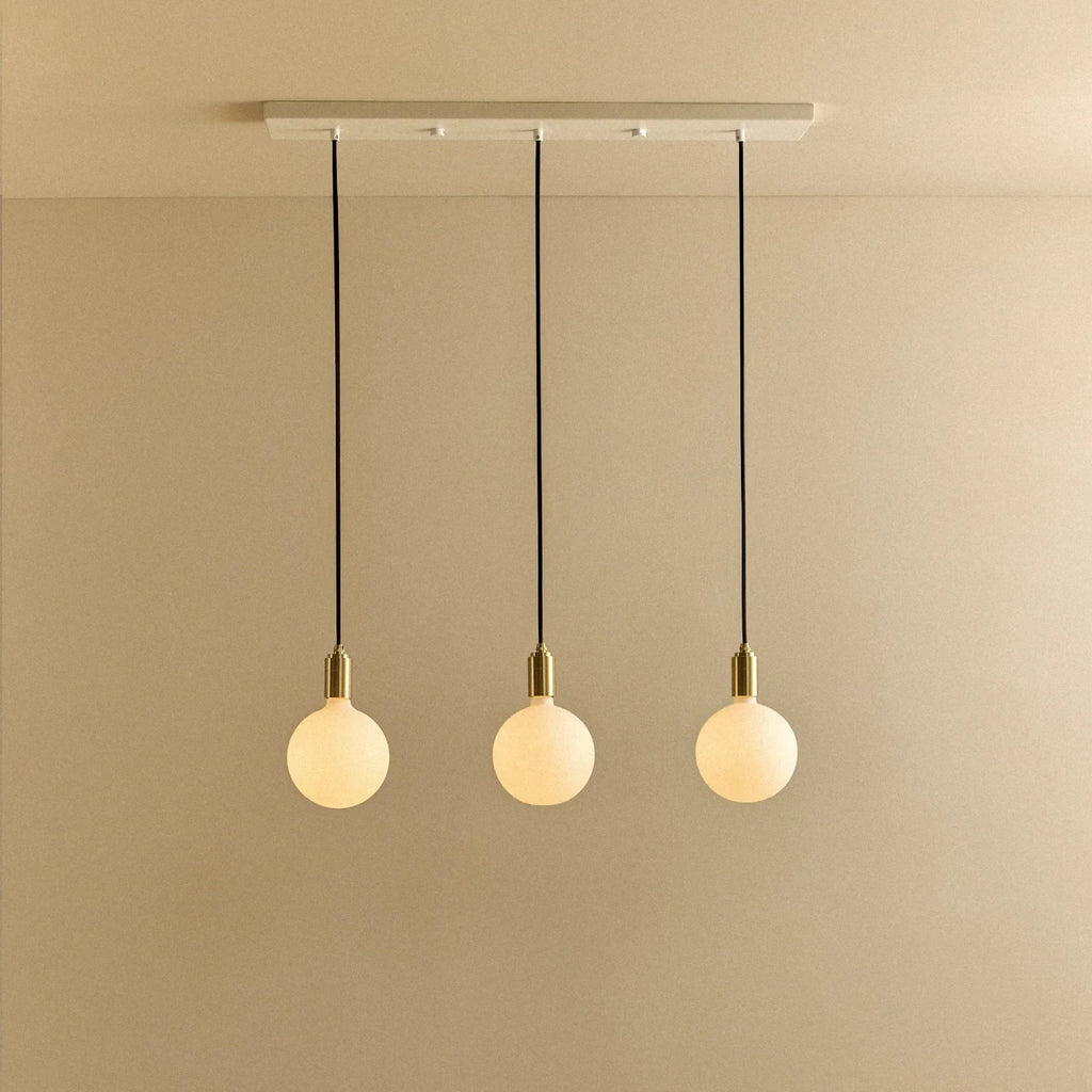 Linear triple opal globe pendant, with white canopy against a plain wall