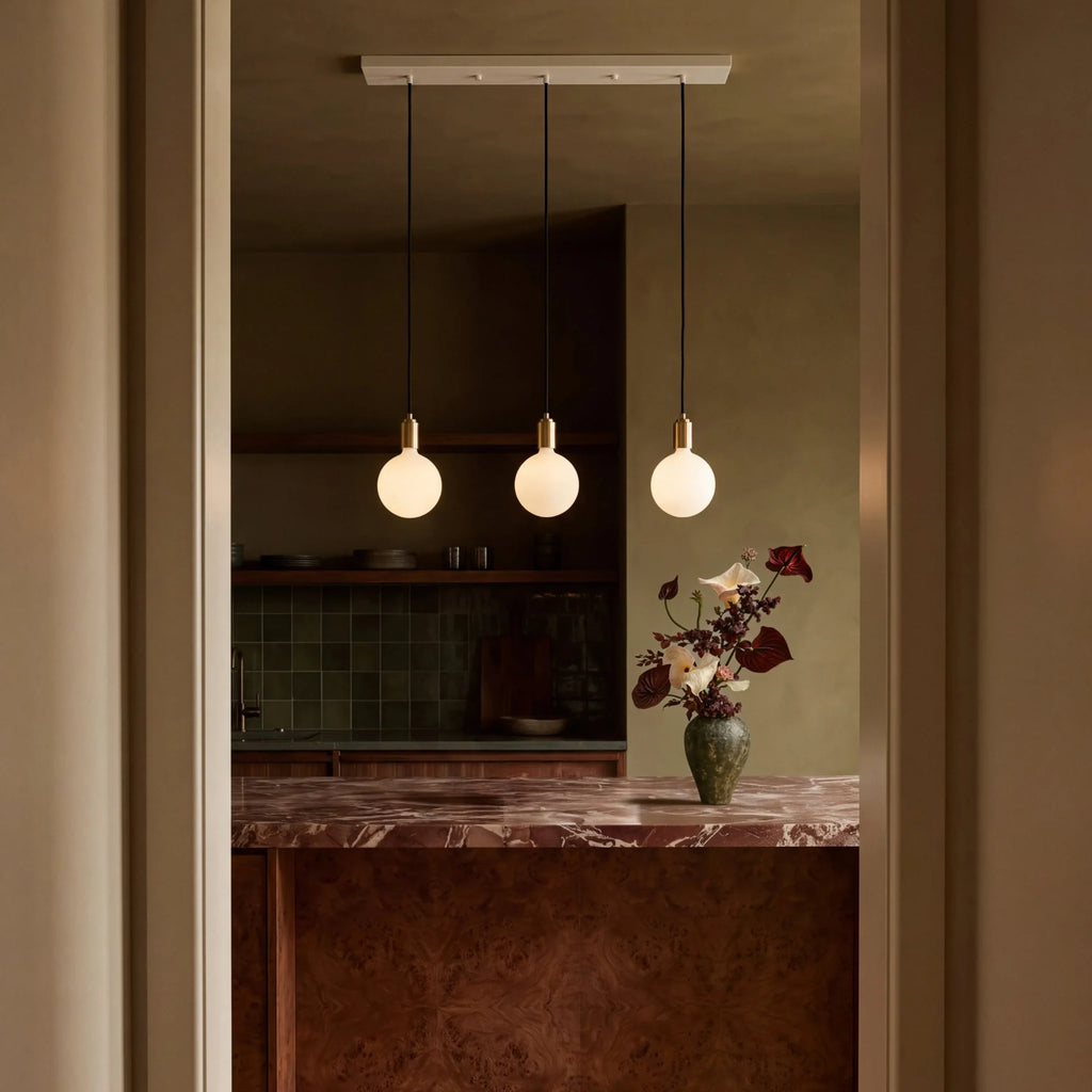 Linear triple opal globe pendant, seen through a doorway above a marble counter