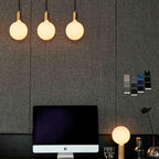 Linear triple opal globe pendant, lit above a desk