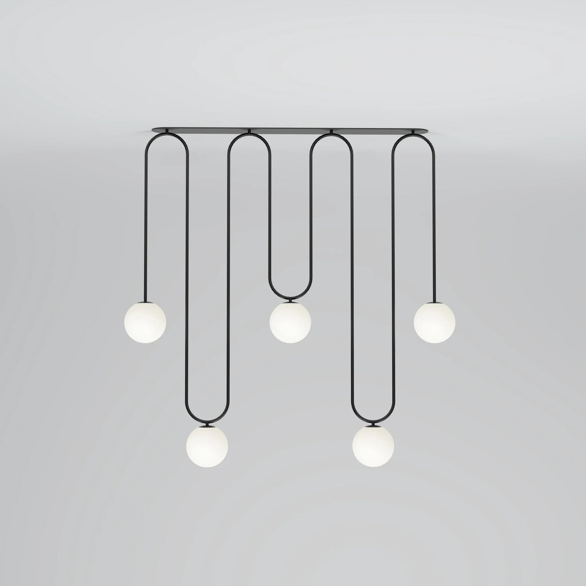 Long looping pendant with five white globes at staggered heights, in black against a grey wall