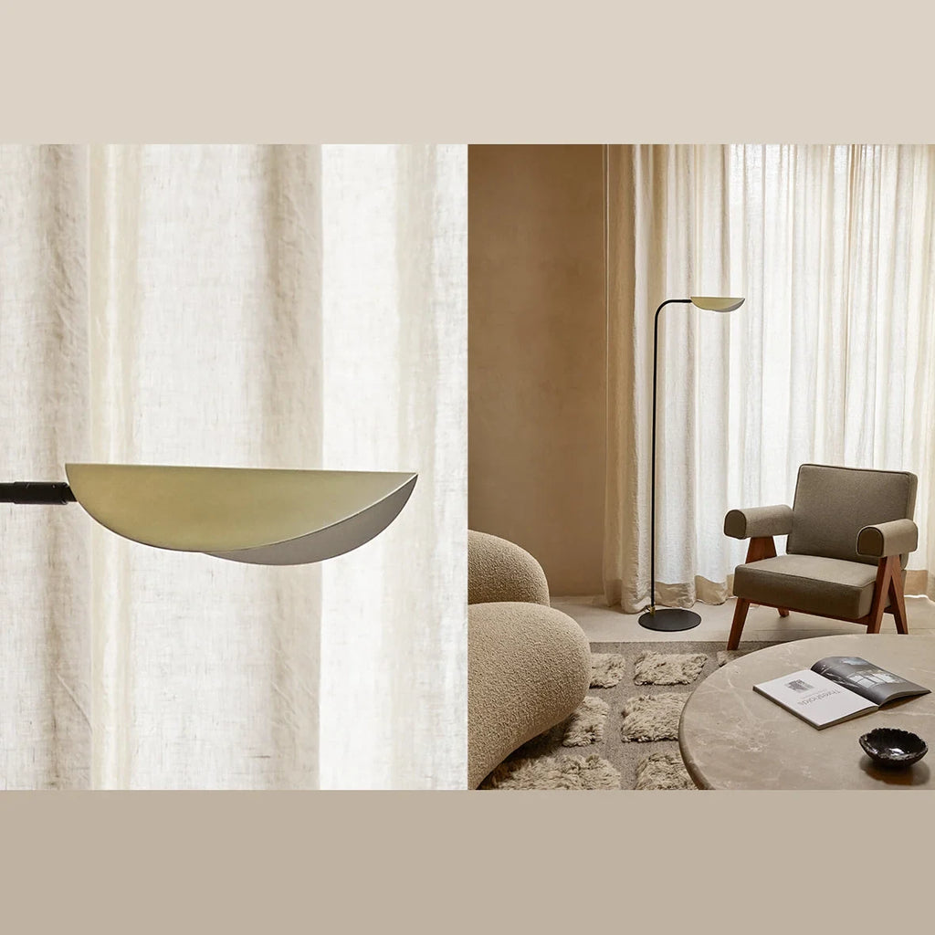 Low-arc reading floor lamp with brass shade, beside a lounge chair in a living room