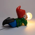 Lying dwarf table lamp with glowing glass bubble, lit, rear three-quarter view